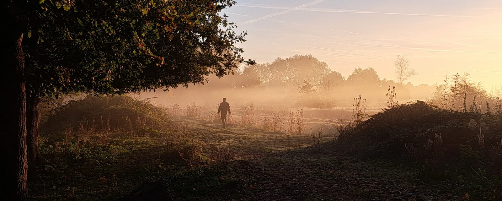 Wandelende man met zonsopgang in de mist